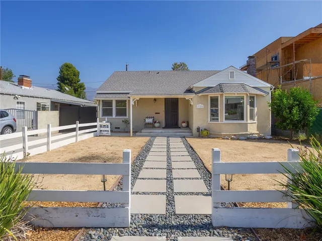 a view of a white house with large windows next to a yard