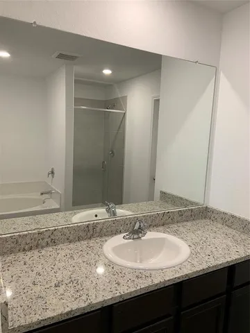 a bathroom with a granite countertop sink and a mirror