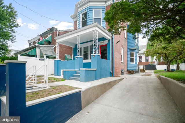 a view of a white house with large windows and a small yard
