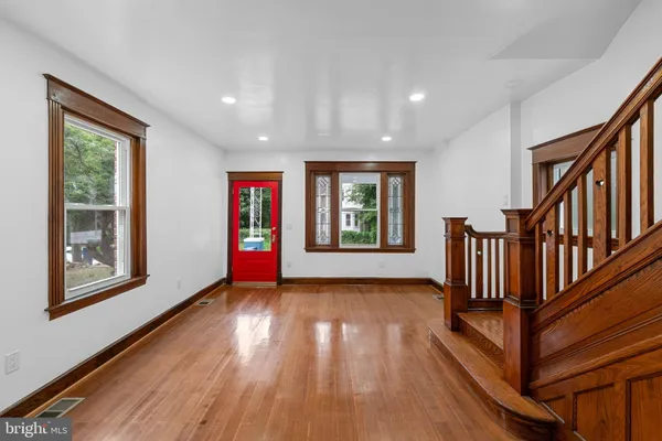 a view of an empty room with wooden floor and windows