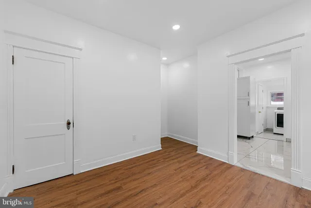 a view of a hallway with wooden floor and a bathroom