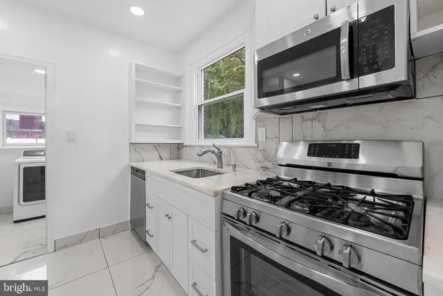 a kitchen with stainless steel appliances granite countertop white cabinets a stove top oven a sink and dishwasher