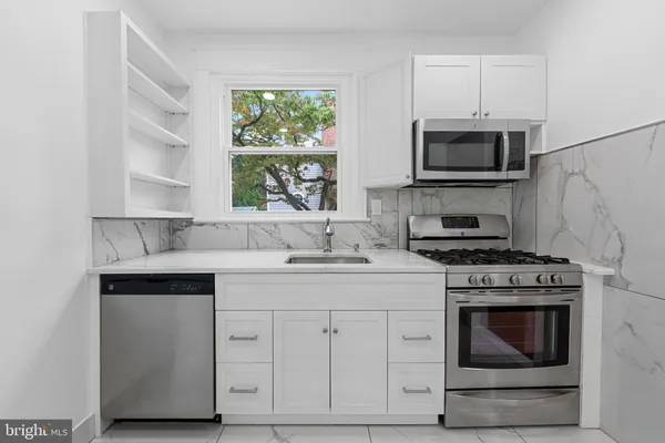 a kitchen with white cabinets stainless steel appliances and sink