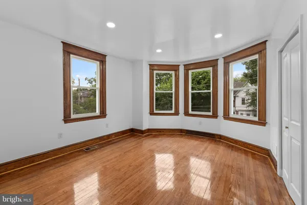 a view of an empty room with wooden floor and closet