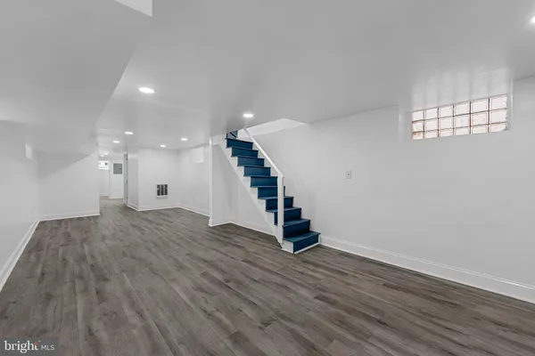 a view of an empty room with wooden floor and staircase