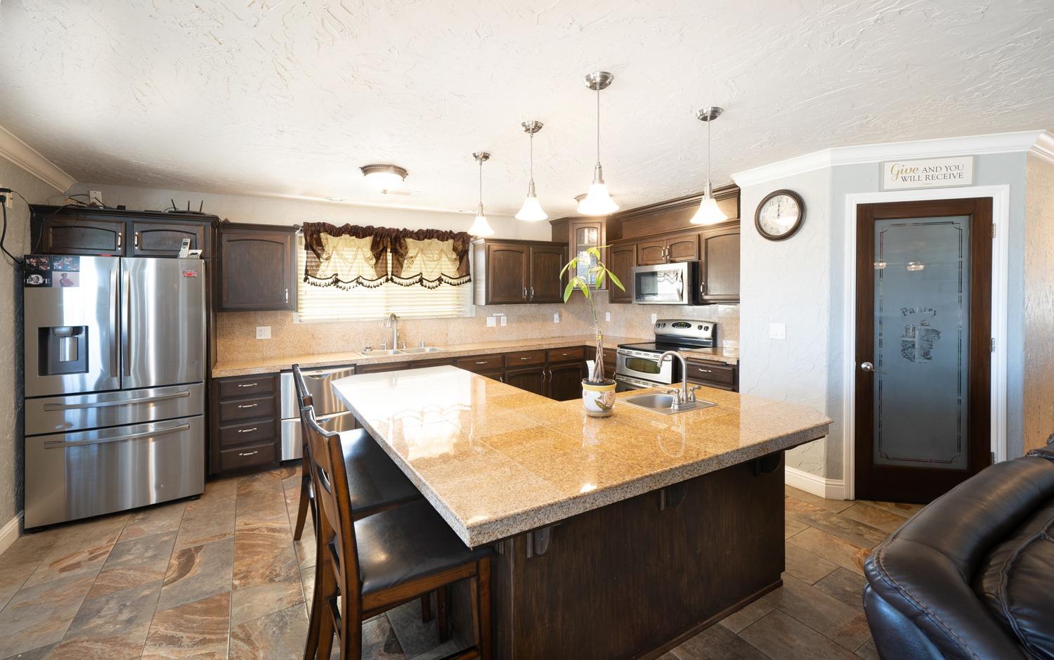21197 Steward Road Madera, CA 93638 - Photo 15 of 41 a kitchen with stainless steel appliances granite countertop a refrigerator a stove and a sink with wooden floor