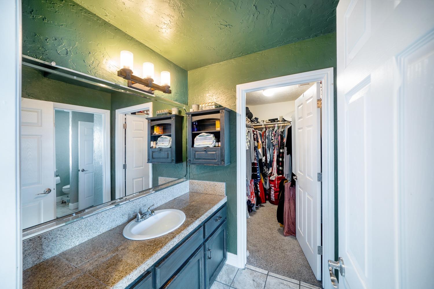 21197 Steward Road Madera, CA 93638 - Photo 28 of 41 a bathroom with a granite countertop sink a mirror and shower