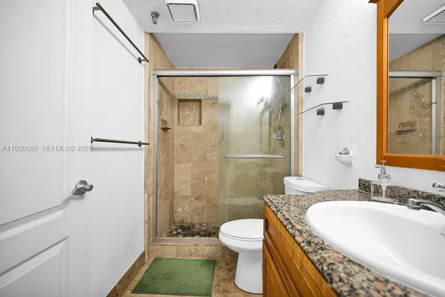 a bathroom with a granite countertop sink a toilet and shower