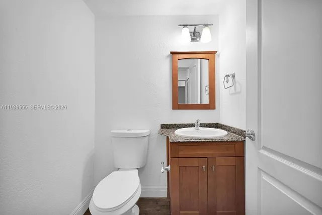 a bathroom with a granite countertop toilet a sink and mirror