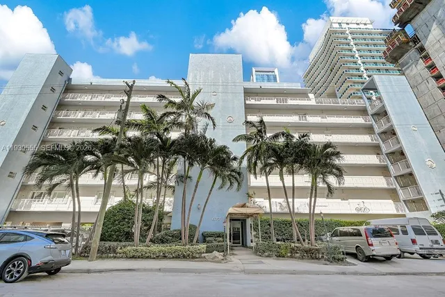 a front view of multi story residential apartment building with yard and parking space