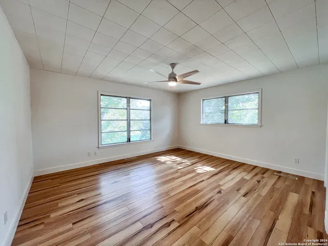 a view of an empty room with wooden floor and a window