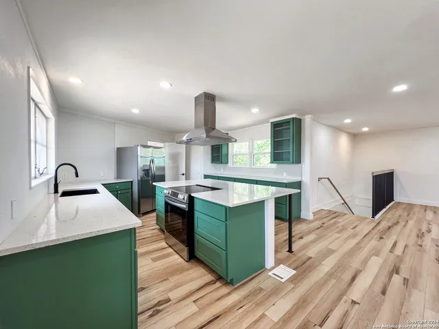 a kitchen with stainless steel appliances granite countertop a sink a stove and a wooden floors