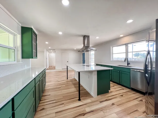 a kitchen with stainless steel appliances kitchen island granite countertop a sink and wooden floors