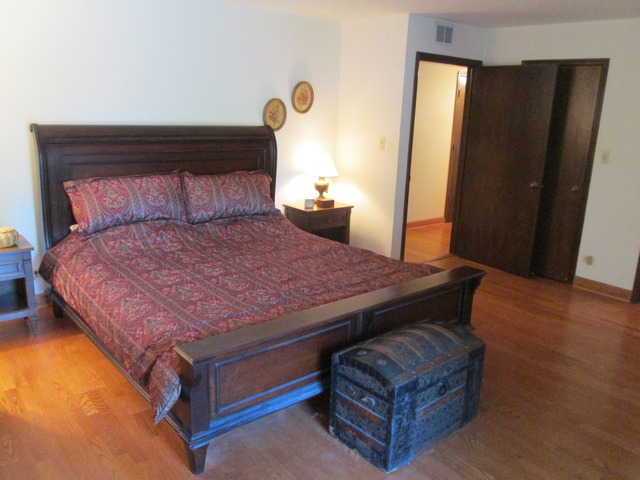 75 Boardwalk Place, Unit 101 Park Ridge, IL 60068 - Photo 10 of 16 a bedroom with a bed and wooden floor