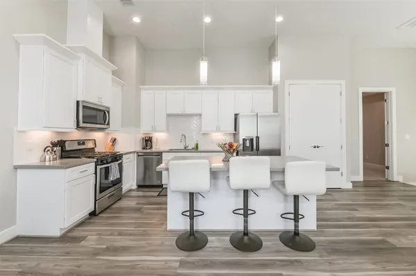 a living room with stainless steel appliances kitchen island granite countertop a dining table chairs refrigerator and sink