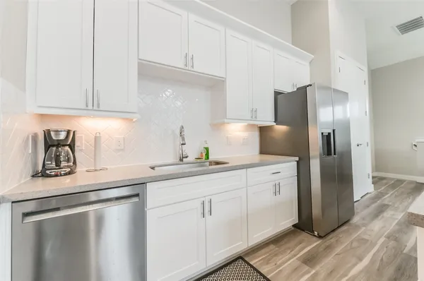 a kitchen with white cabinets sink and refrigerator
