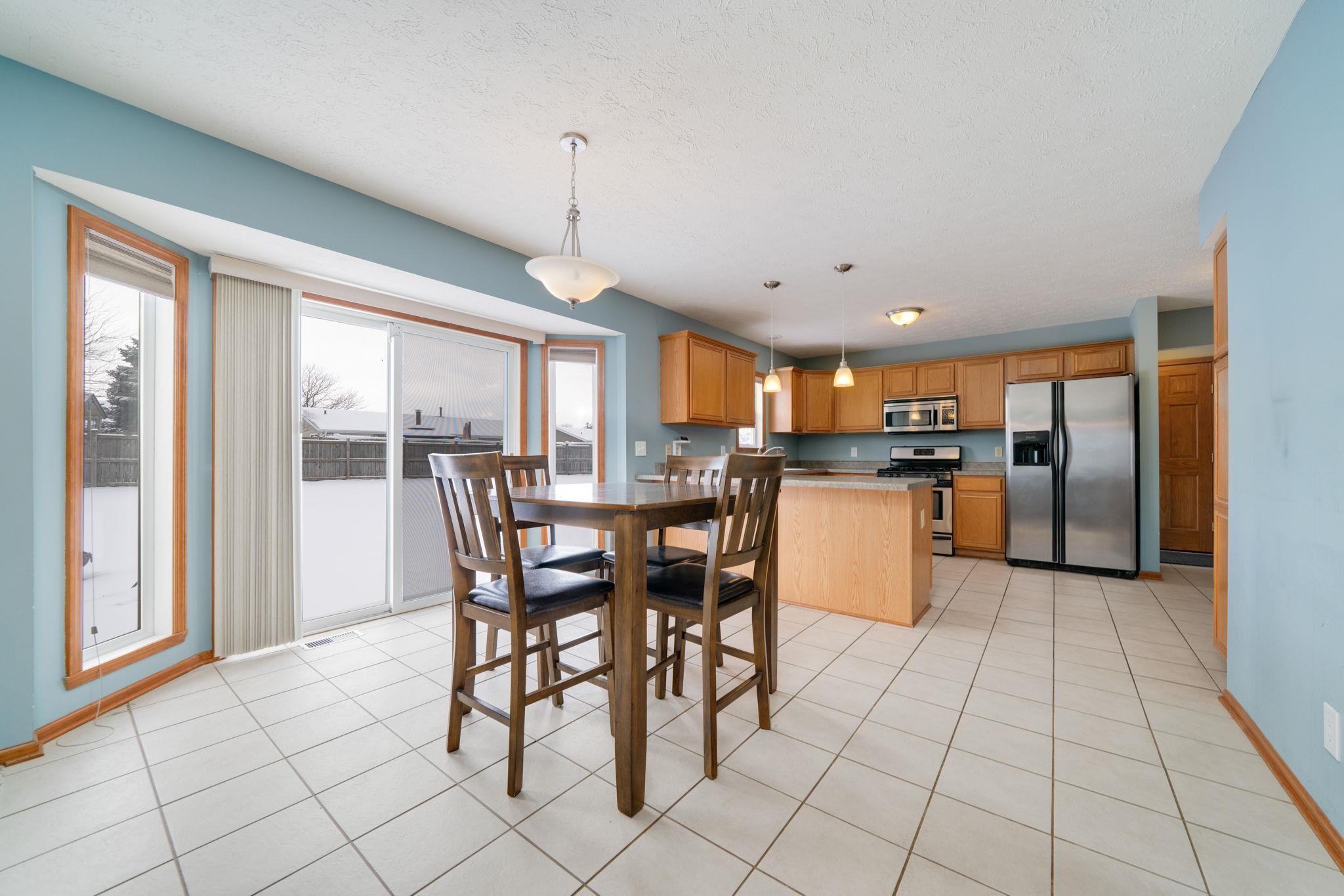 11062 Chicory Ridge Way Roscoe, IL 61073 - Photo 13 of 43 a kitchen with stainless steel appliances kitchen island granite countertop a refrigerator a stove a dining table and chairs with wooden floor