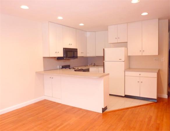 150 Beaconsfield Road, Unit 5 Brookline, MA 02445 - Photo 1 of 7 a kitchen with a refrigerator a stove top oven a sink and white cabinets
