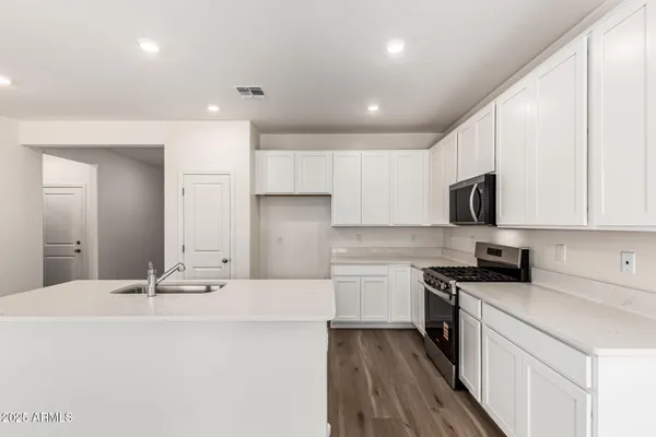 a kitchen with stainless steel appliances a sink stove and white cabinets