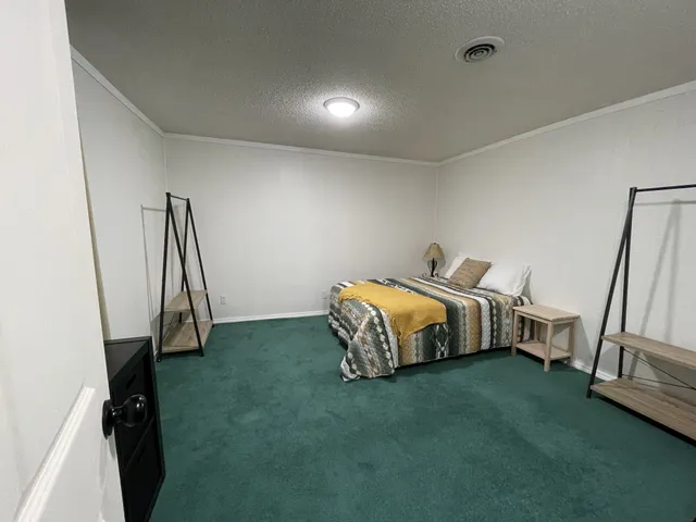 a bedroom with a bed and a flat tv screen on the dresser
