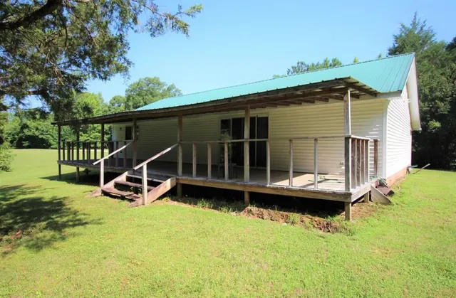 a view of a house with a backyard and a wooden deck