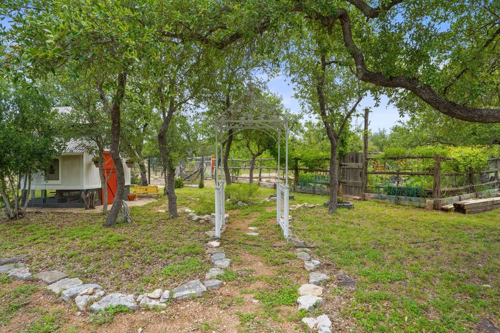 290 Sunset Ridge Dripping Springs, TX 78620 - Photo 34 of 37 A charming garden archway invites you through the verdant landscape to a raised-bed vegetable patch and a cozy cottage.