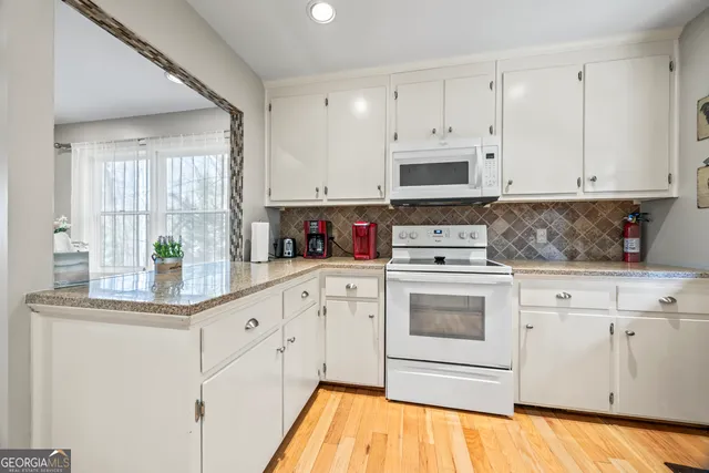 a kitchen with stainless steel appliances granite countertop a stove a sink and white cabinets
