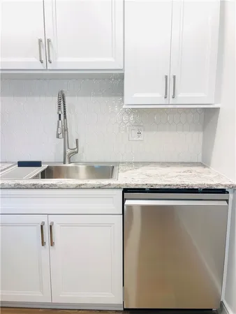 a kitchen with granite countertop white cabinets and a sink