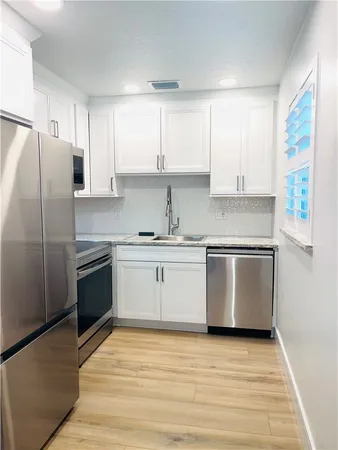 a kitchen with granite countertop white cabinets and stainless steel appliances