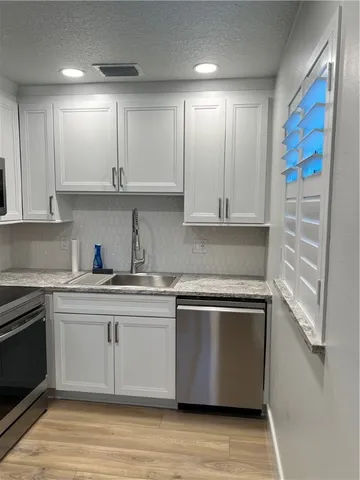 a kitchen with stainless steel appliances granite countertop a stove a sink and white cabinets