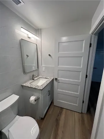 a bathroom with a granite countertop toilet sink and mirror
