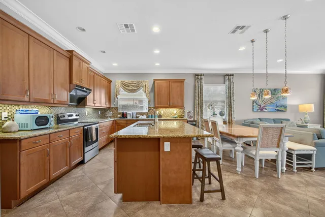 a kitchen with stainless steel appliances granite countertop a stove top oven a sink dishwasher a dining table and chairs with wooden floor