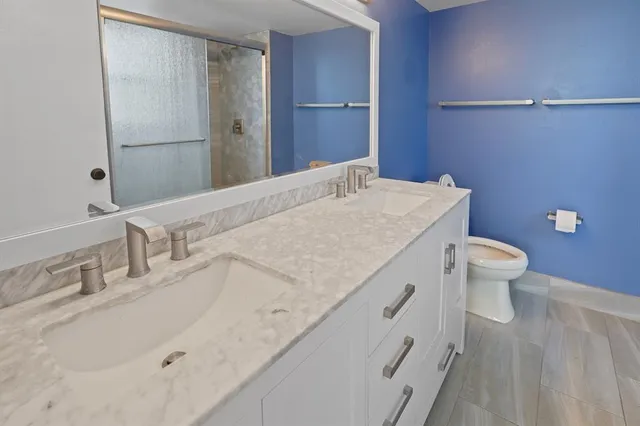 a bathroom with a granite countertop sink a toilet and a mirror