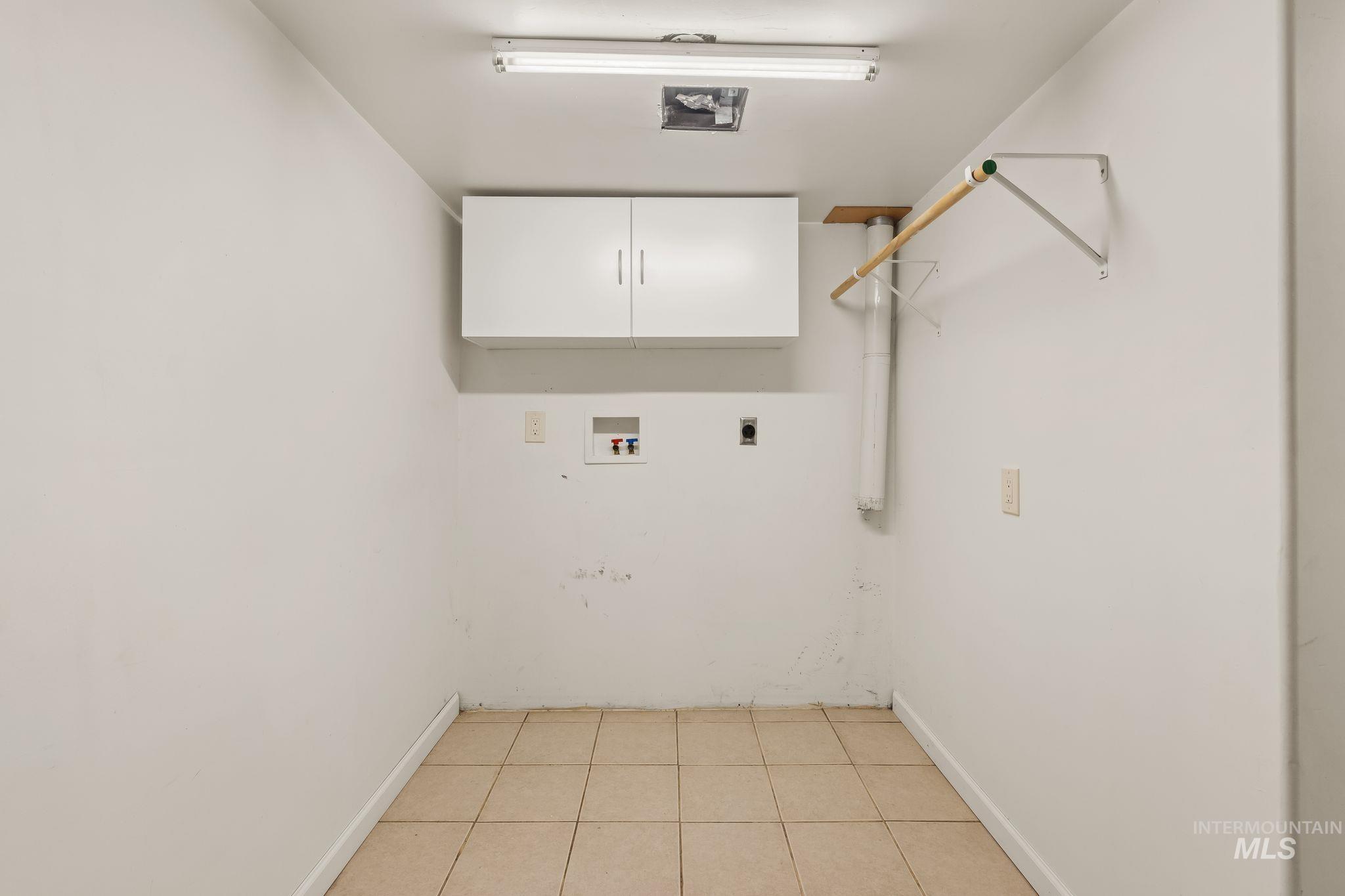 928 3rd Street Clarkston, WA 99403 - Photo 26 of 44 Laundry area featuring tile flooring, wall-mounted cabinetry, a clothes hanging rod, and utility hookups