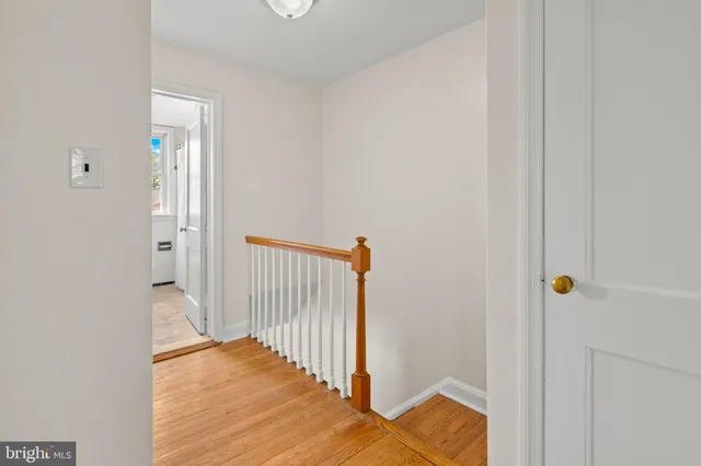 a view of a hallway with wooden floor and a bathroom