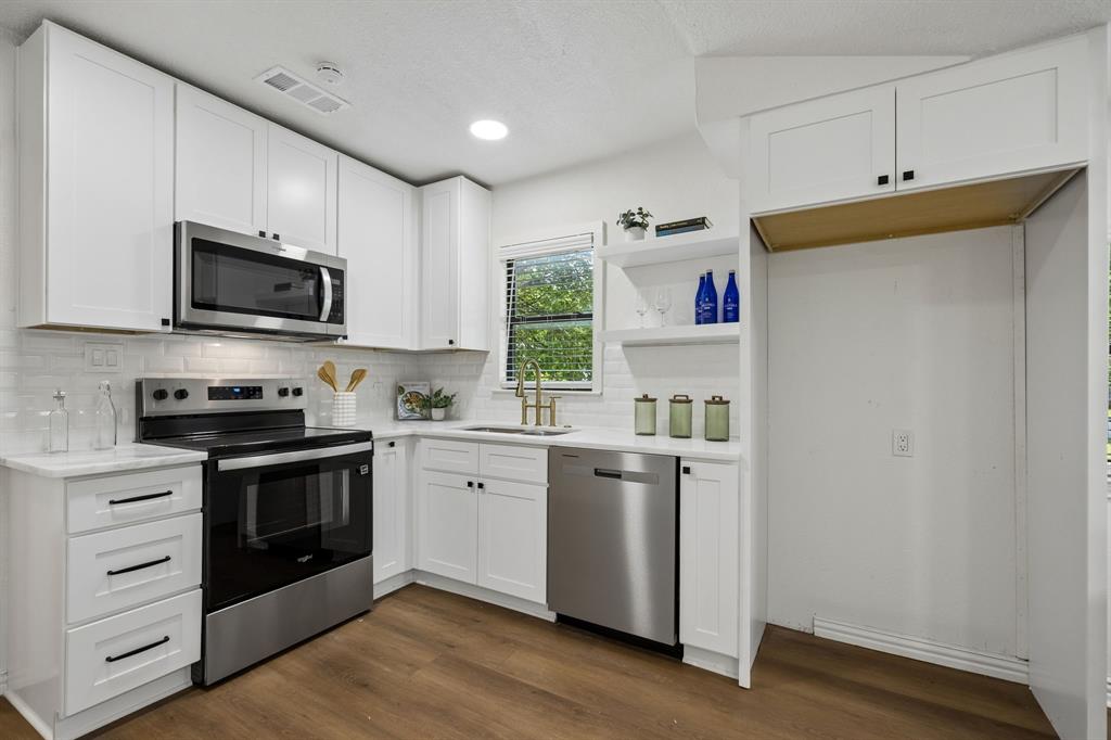 806 North Ruddell Street Denton, TX 76209 - Photo 12 of 26 a kitchen with stainless steel appliances granite countertop a stove a sink and a microwave