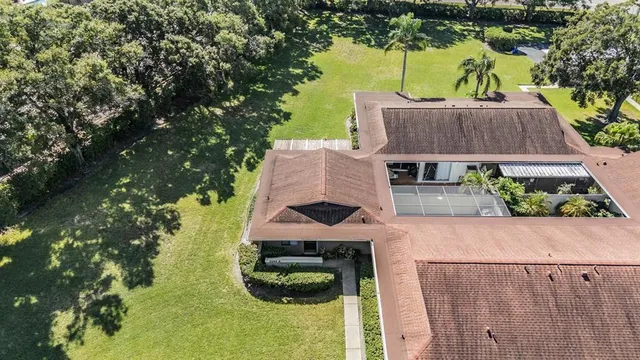 an aerial view of a house with swimming pool and large trees
