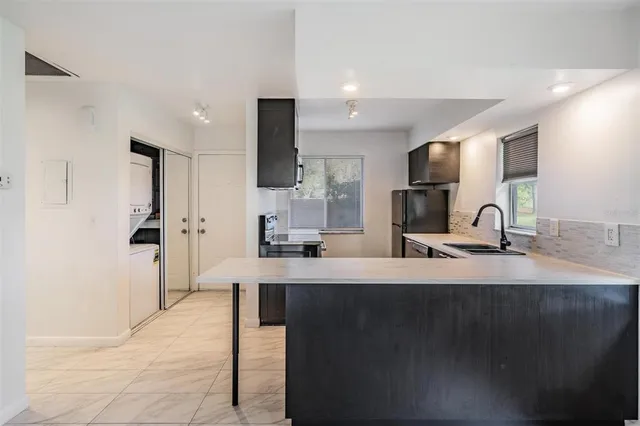 a kitchen with kitchen island a sink appliances and a counter top space