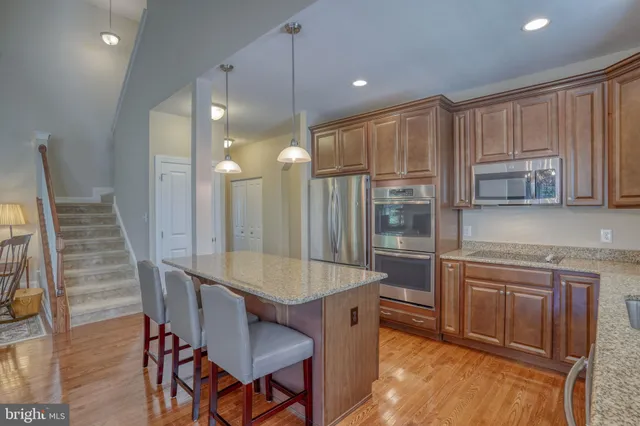 a kitchen with stainless steel appliances granite countertop wooden floor sink and cabinets