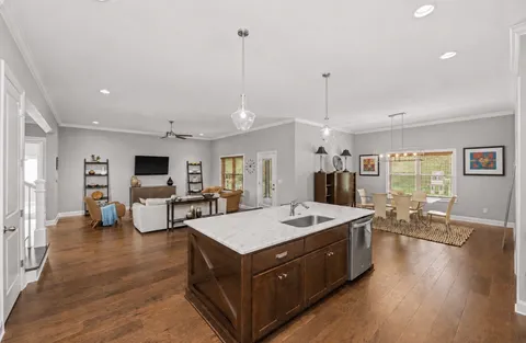 a living room with stainless steel appliances granite countertop furniture wooden floor and a view of kitchen