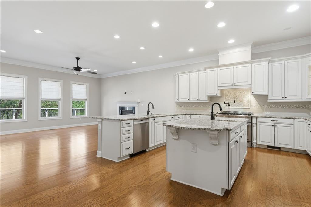 655 Hemlock Trail Canton, GA 30114 - Photo 26 of 58 a large kitchen with stainless steel appliances granite countertop a large center island a stove a sink a refrigerator and white cabinets with wooden floor