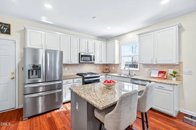 a kitchen with granite countertop kitchen island stainless steel appliances a stove a sink a refrigerator a microwave a dining table and chairs