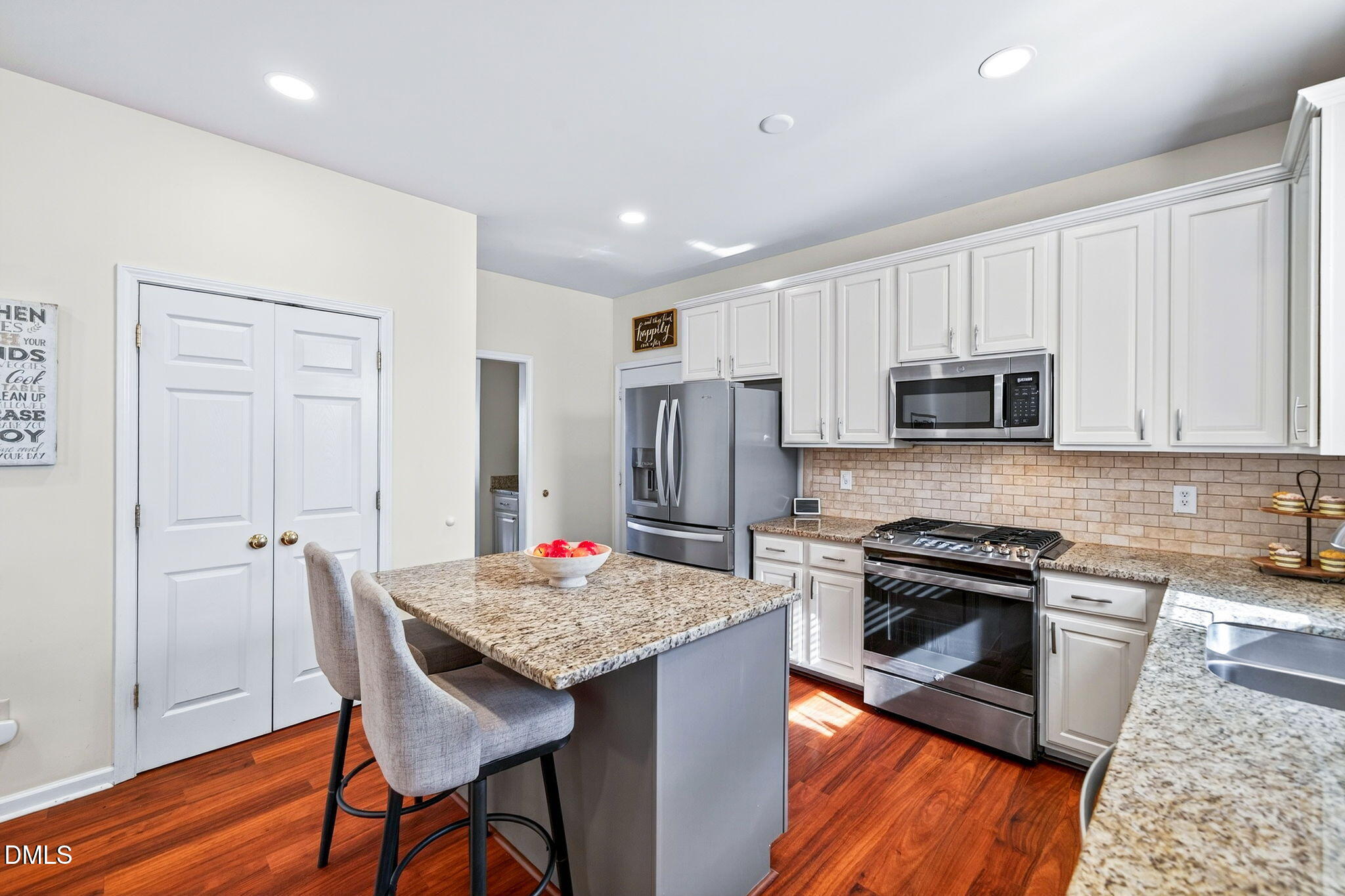 708 Quiet Walk Circle Rolesville, NC 27571 - Photo 8 of 56 a kitchen with granite countertop kitchen island stainless steel appliances a stove a sink a refrigerator a microwave a dining table and chairs