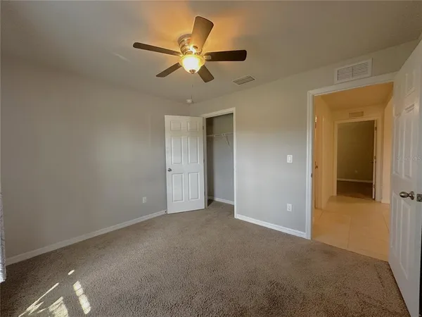 an empty room with closet and ceiling fan