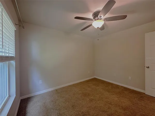 an empty room with closet and a chandelier fan