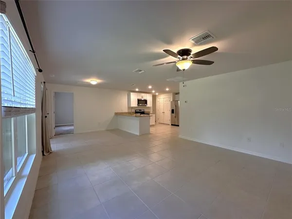 a view of a livingroom with a ceiling fan window and a kitchen view