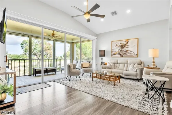 a living room with furniture large window and wooden floor