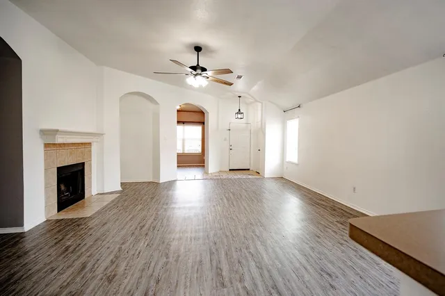 an empty room with wooden floor fireplace and windows