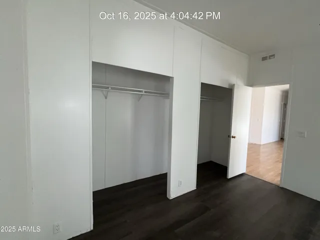 a view of an empty room with wooden floor and closet