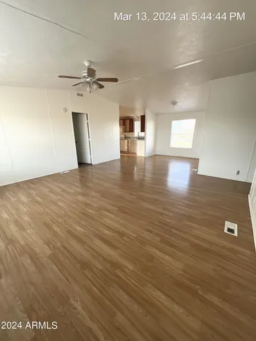 an empty room with wooden floor windows and ceiling fan